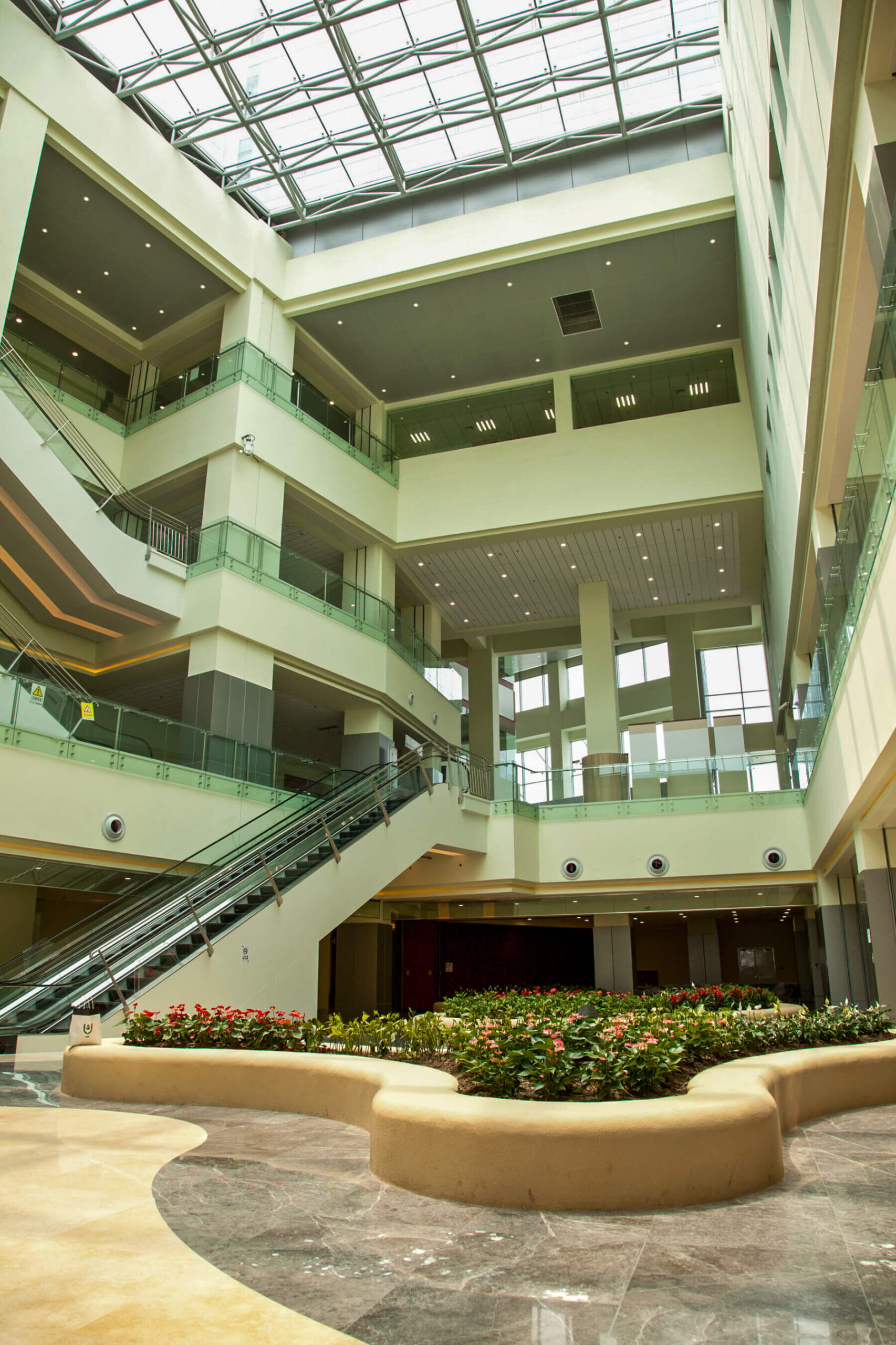 a three-story lobby with escalators and a glass ceiling