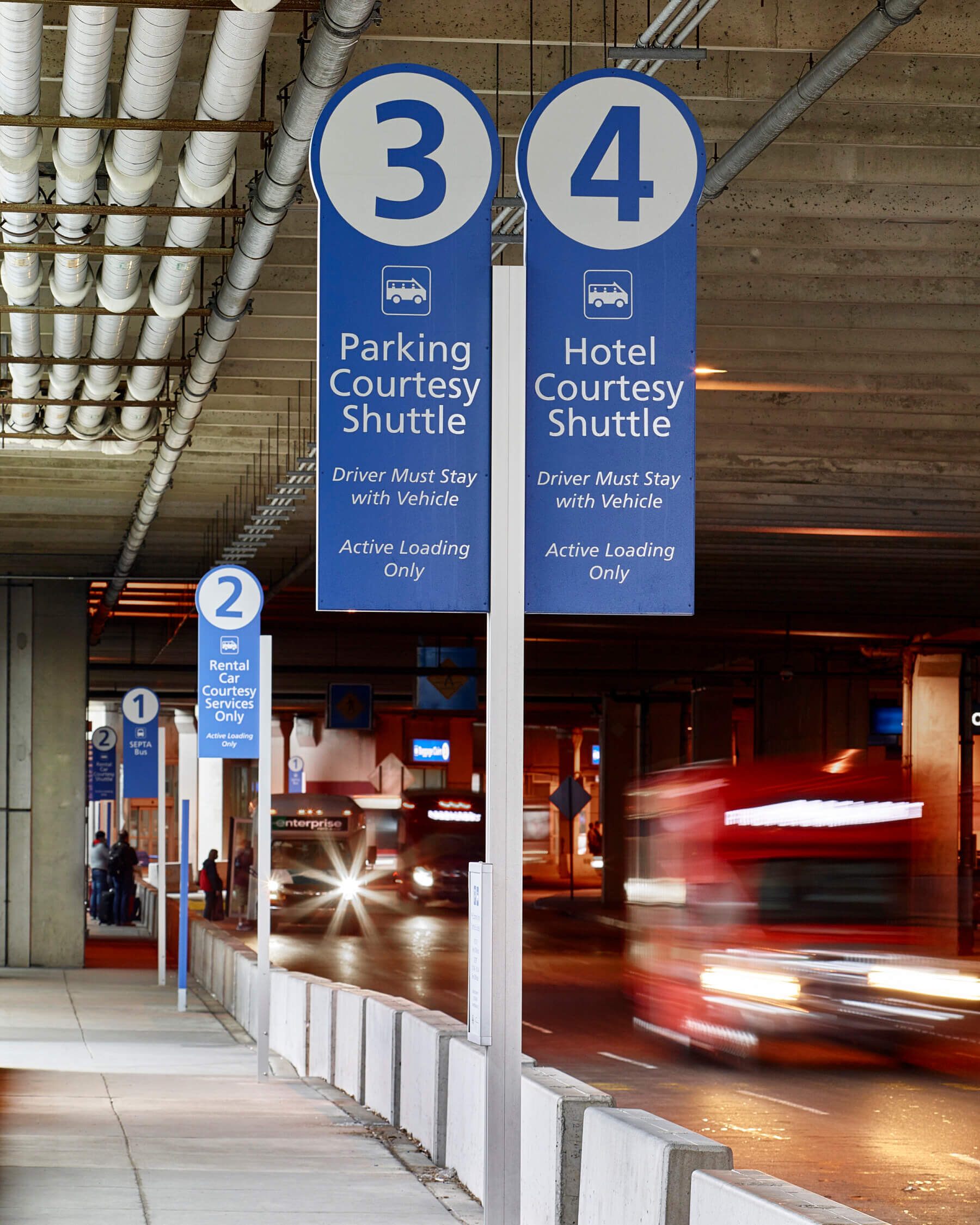 ground-mounted signs on the curbside directing passengers to transportation options outside of Philadelphia International Airport
