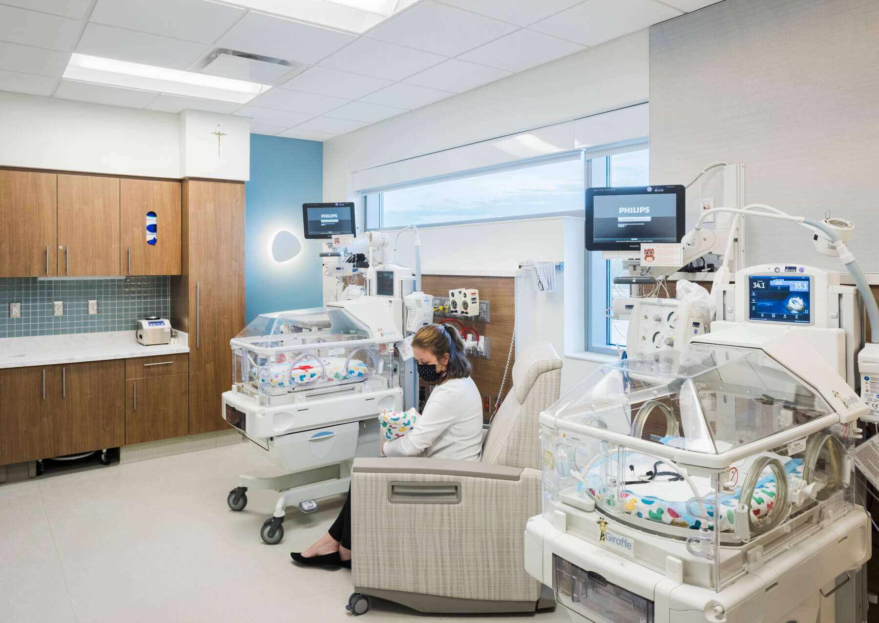 : a woman holding a baby in a neonatal intensive care unit