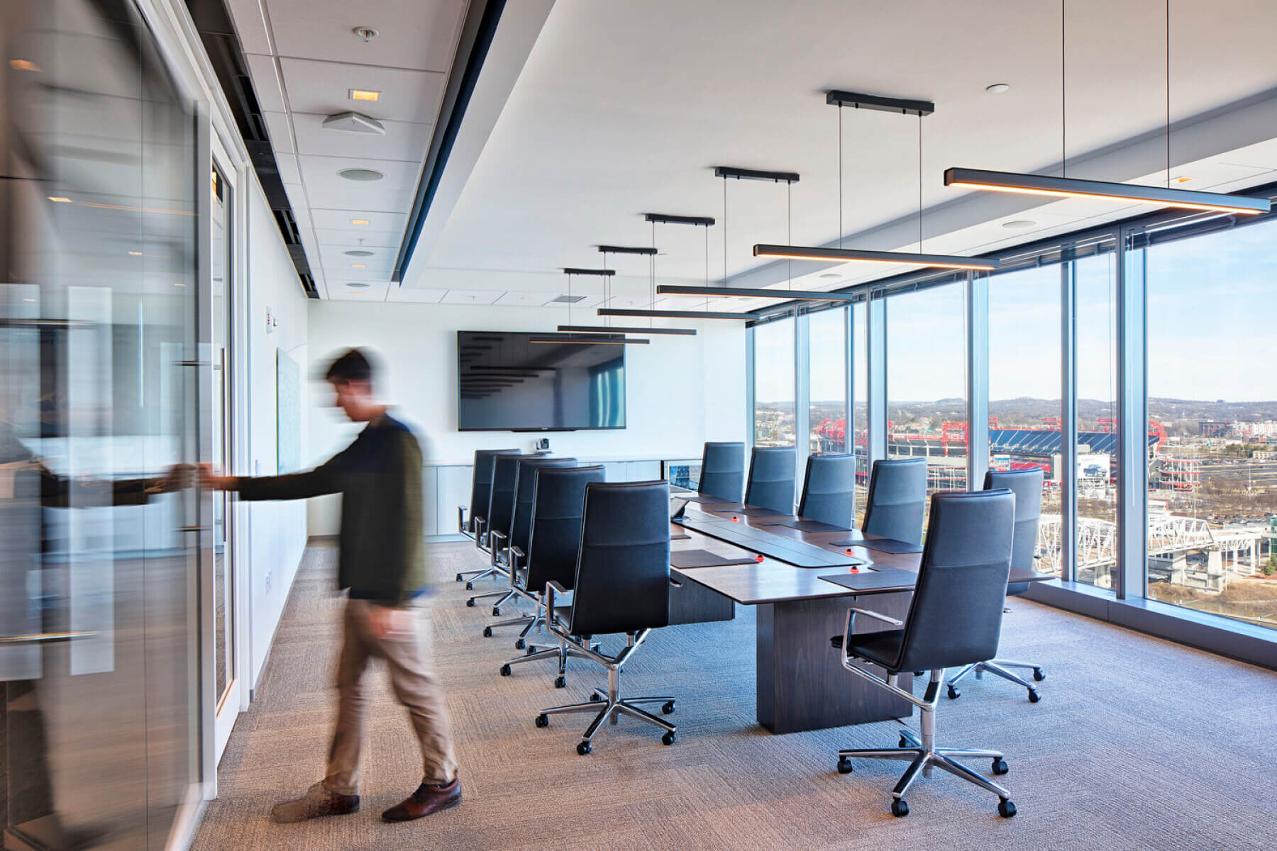 man walks out of boardroom with floor-to-ceiling windows