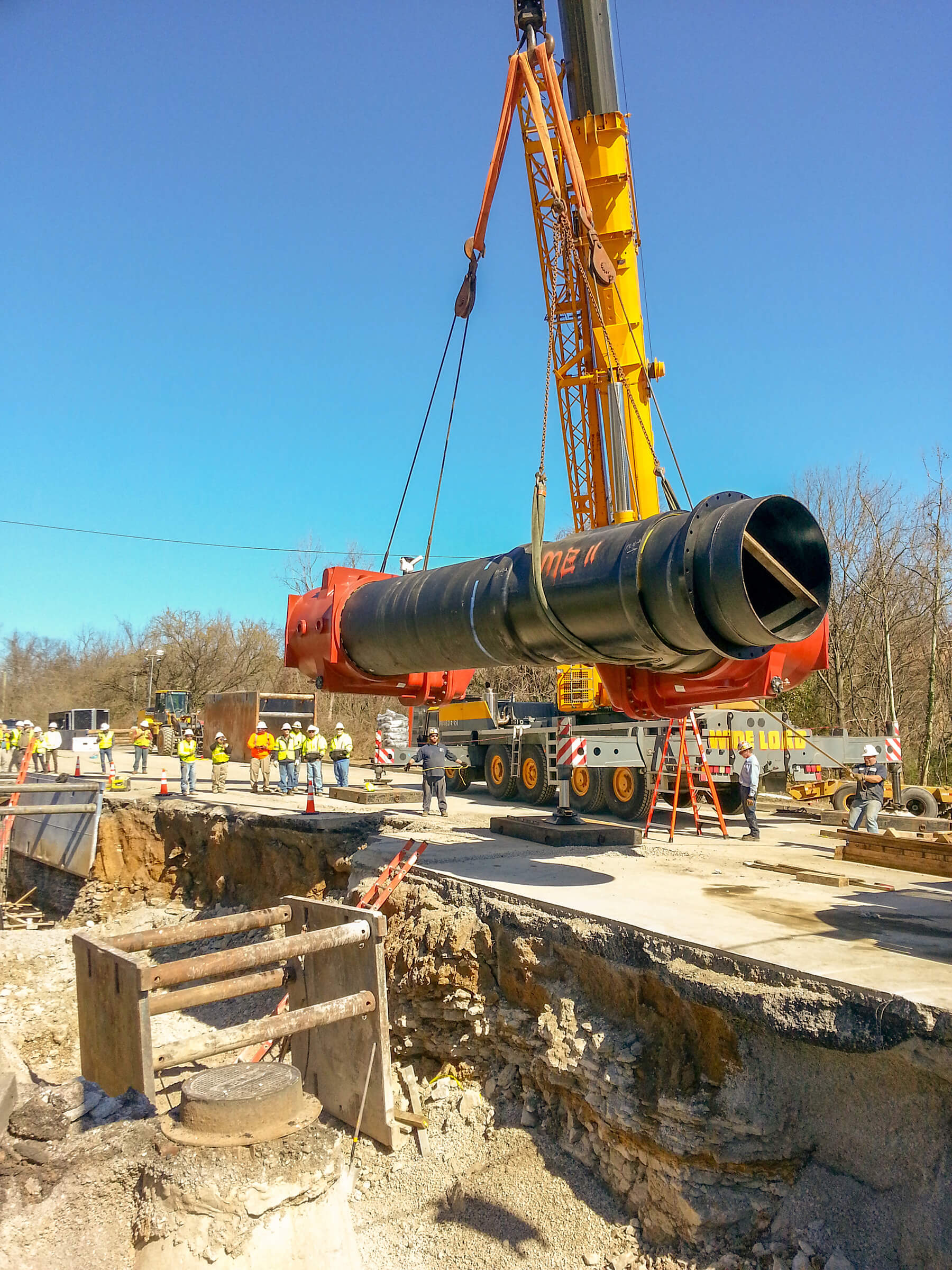 A large pipe being lowered into the ground by a crane