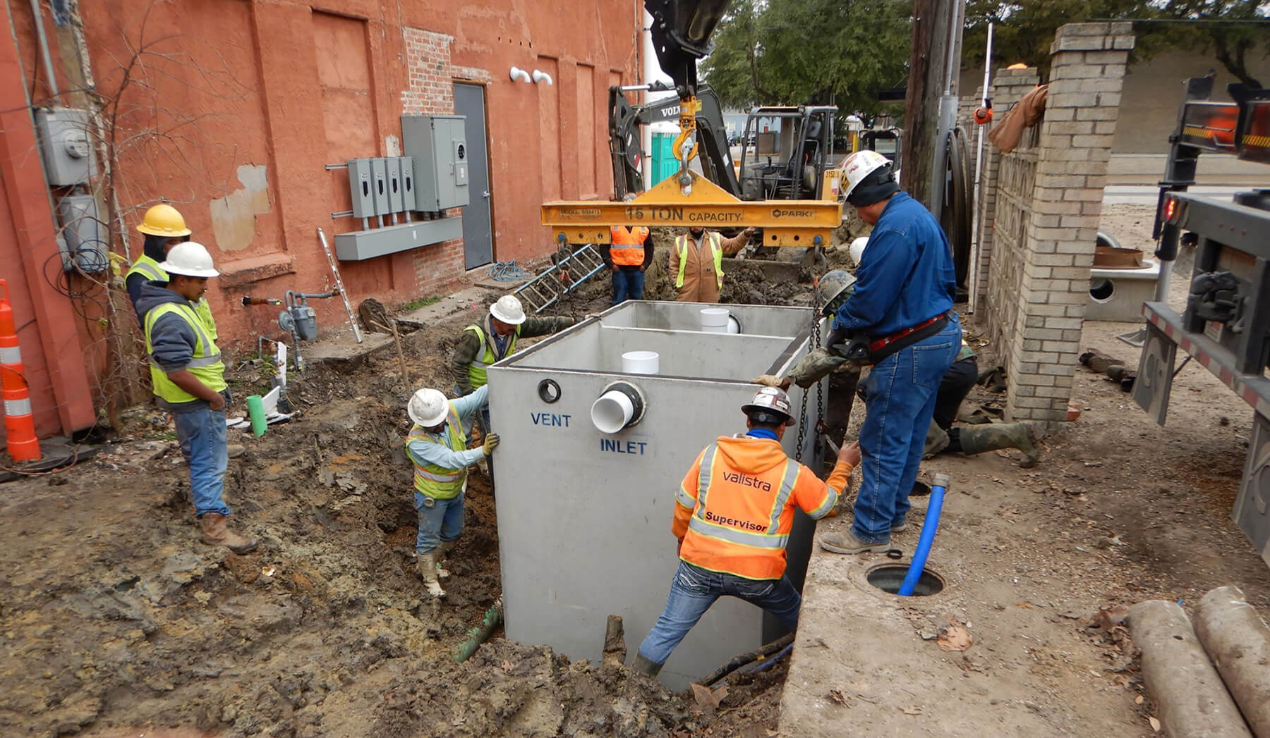 Construction workers install grease trap in alley in downtown Ennis