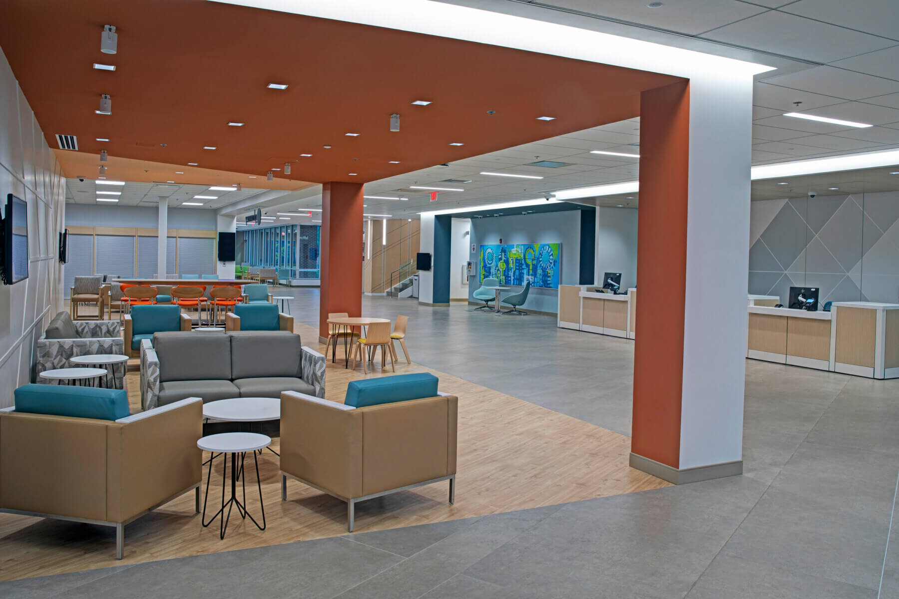 an unoccupied waiting area near the main reception desk, with an orange ceiling and colorful seating