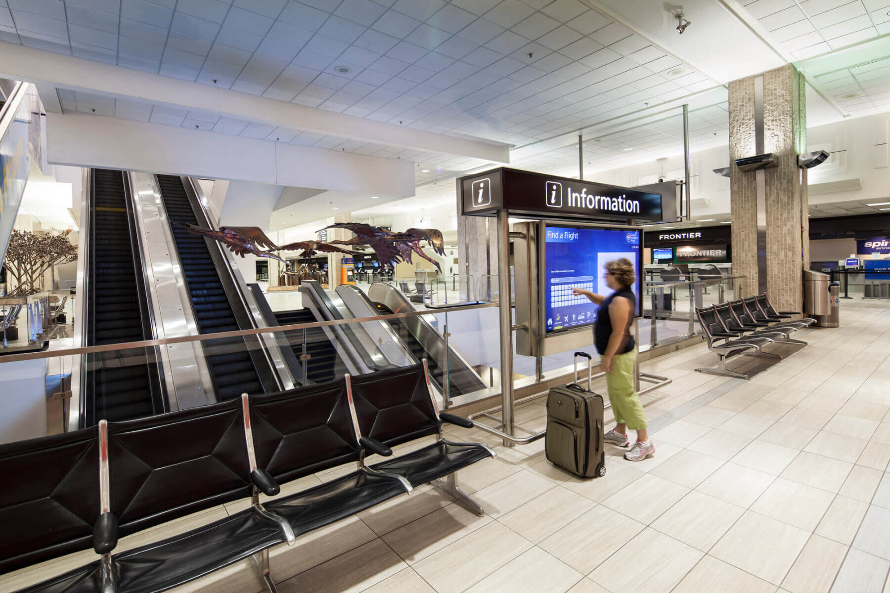 a woman using a digital flight information kiosk in the main terminal at Tampa International Airport