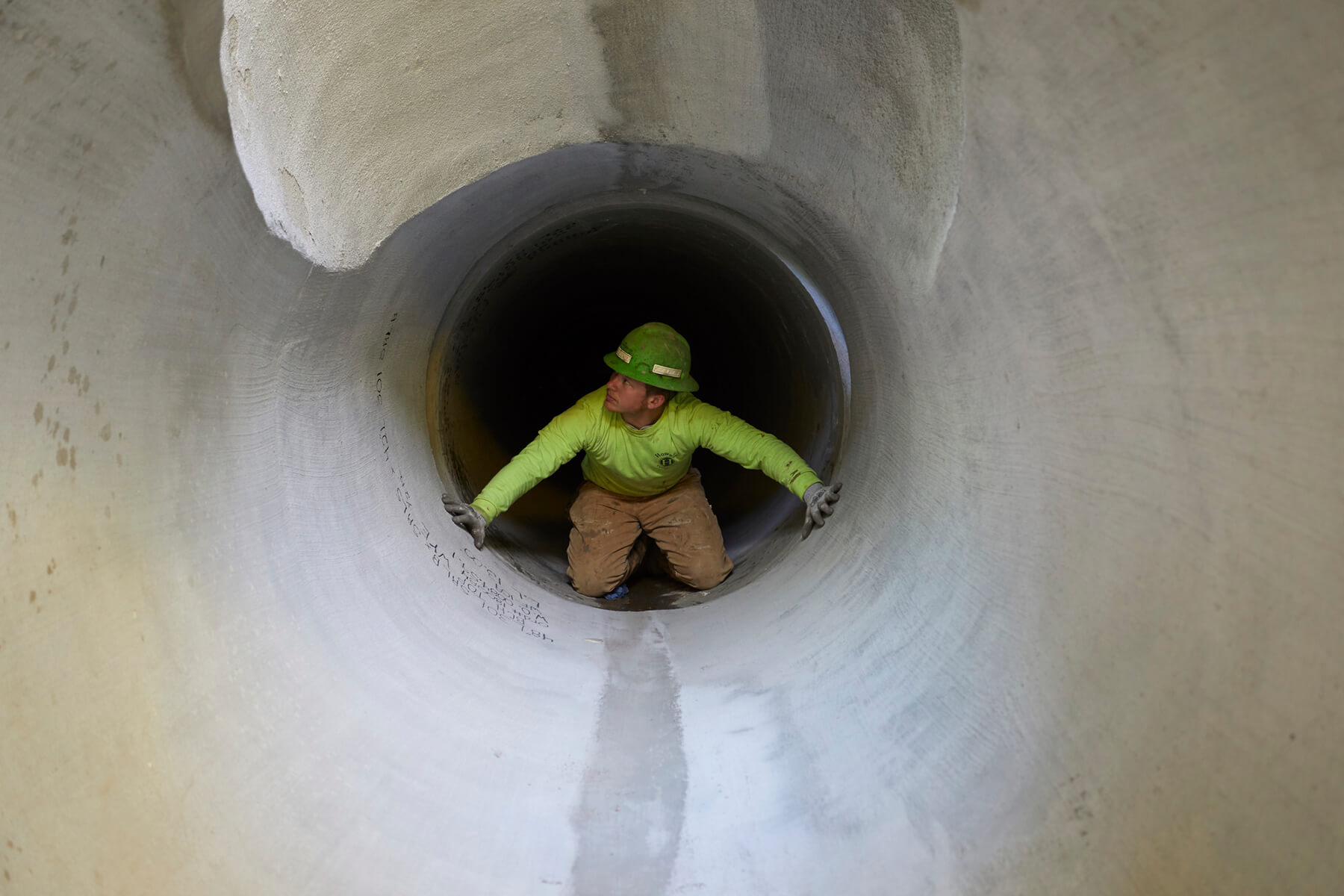 Close-up of worker in concrete cylinder pipe.