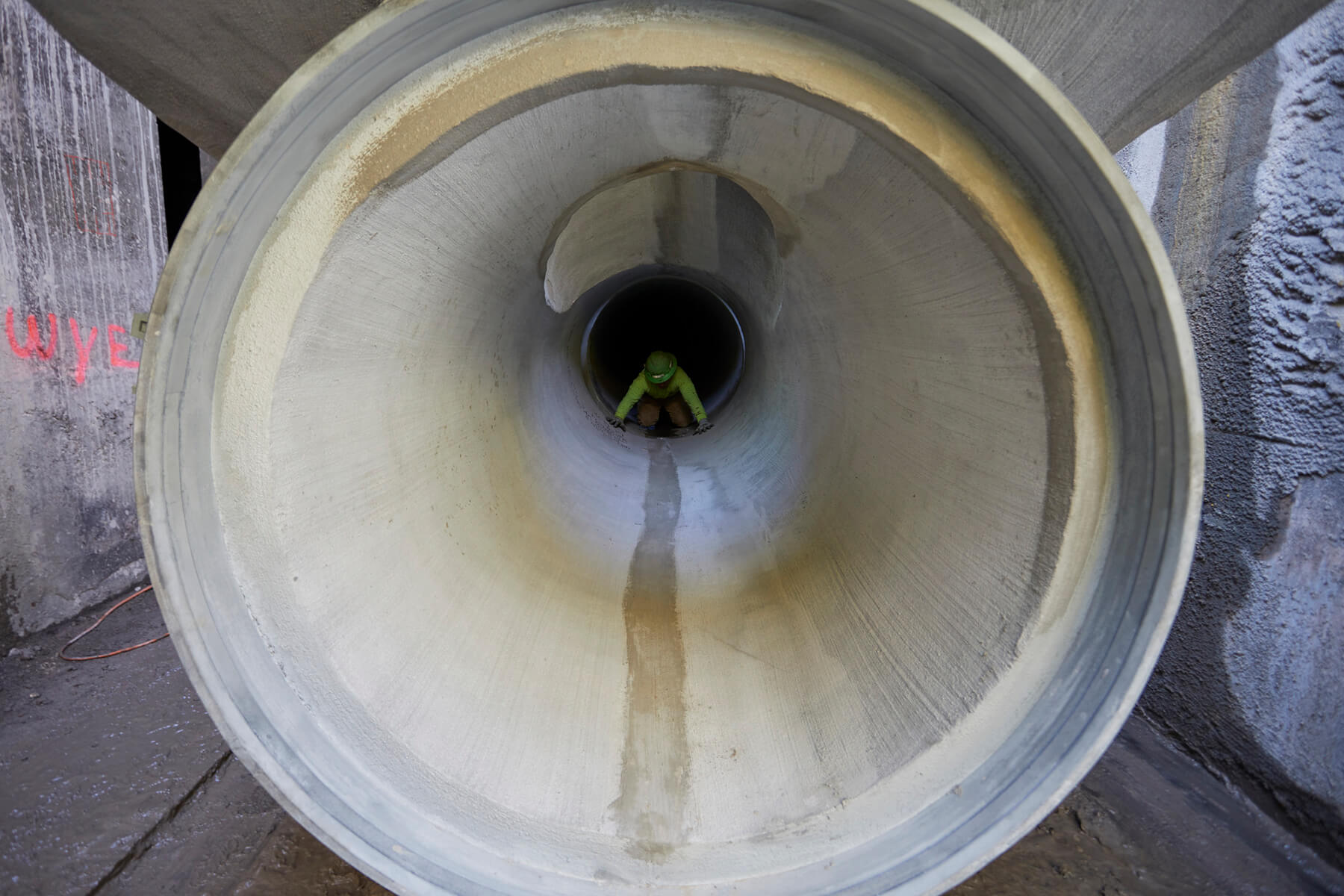 Worker in concrete cylinder pipe as seen from a distance.