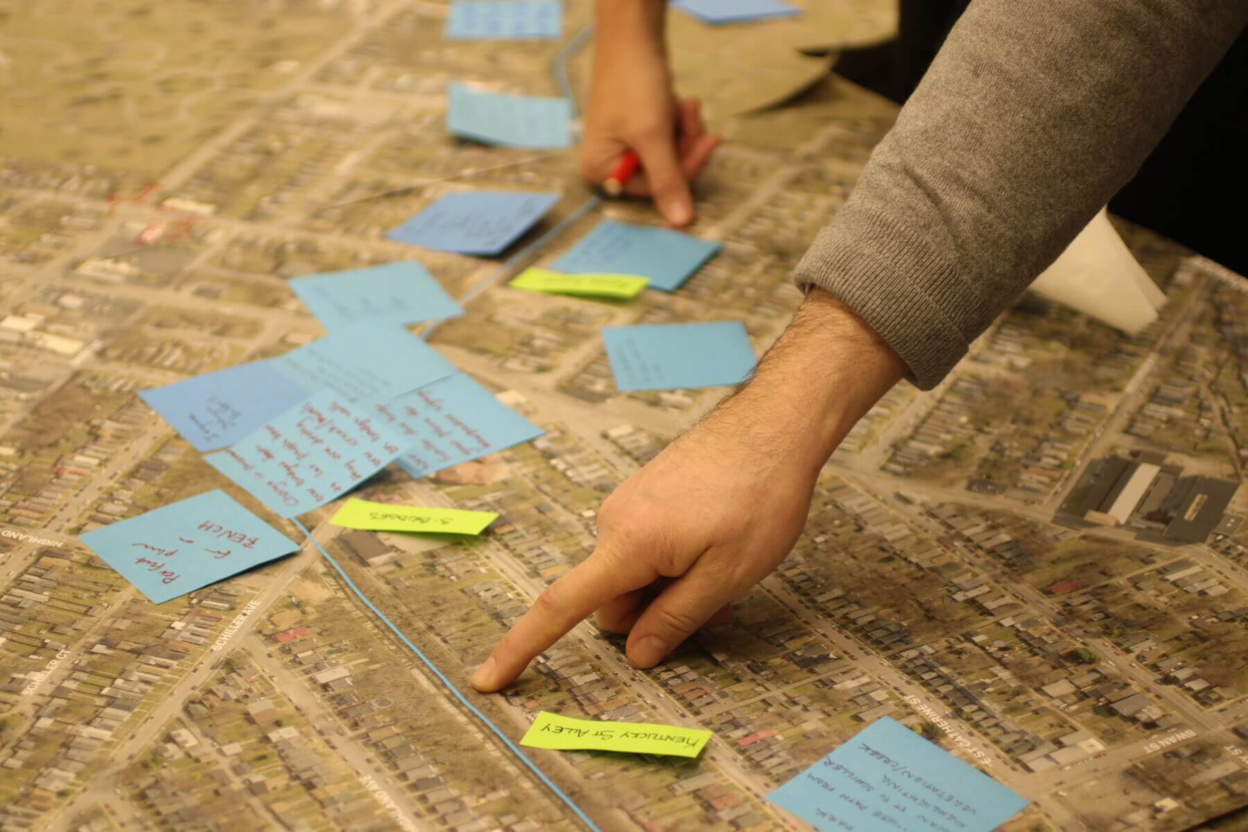 people pointing to post-it notes on a large map