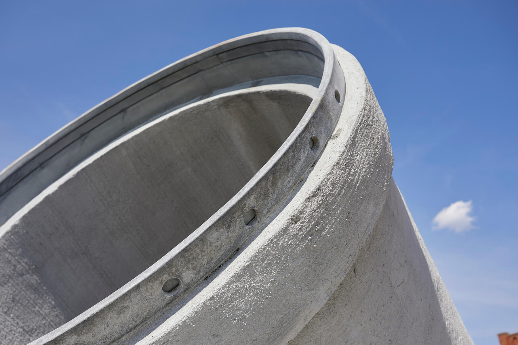 Closeup of a concrete pipe against a blue sky.