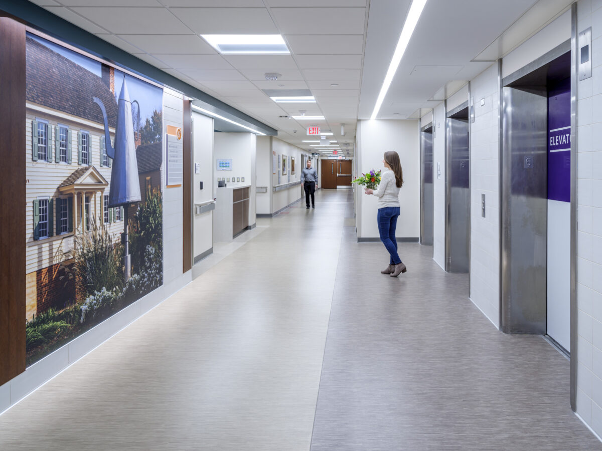 A person holding flowers exiting the elevator on an inpatient floor at a hospital