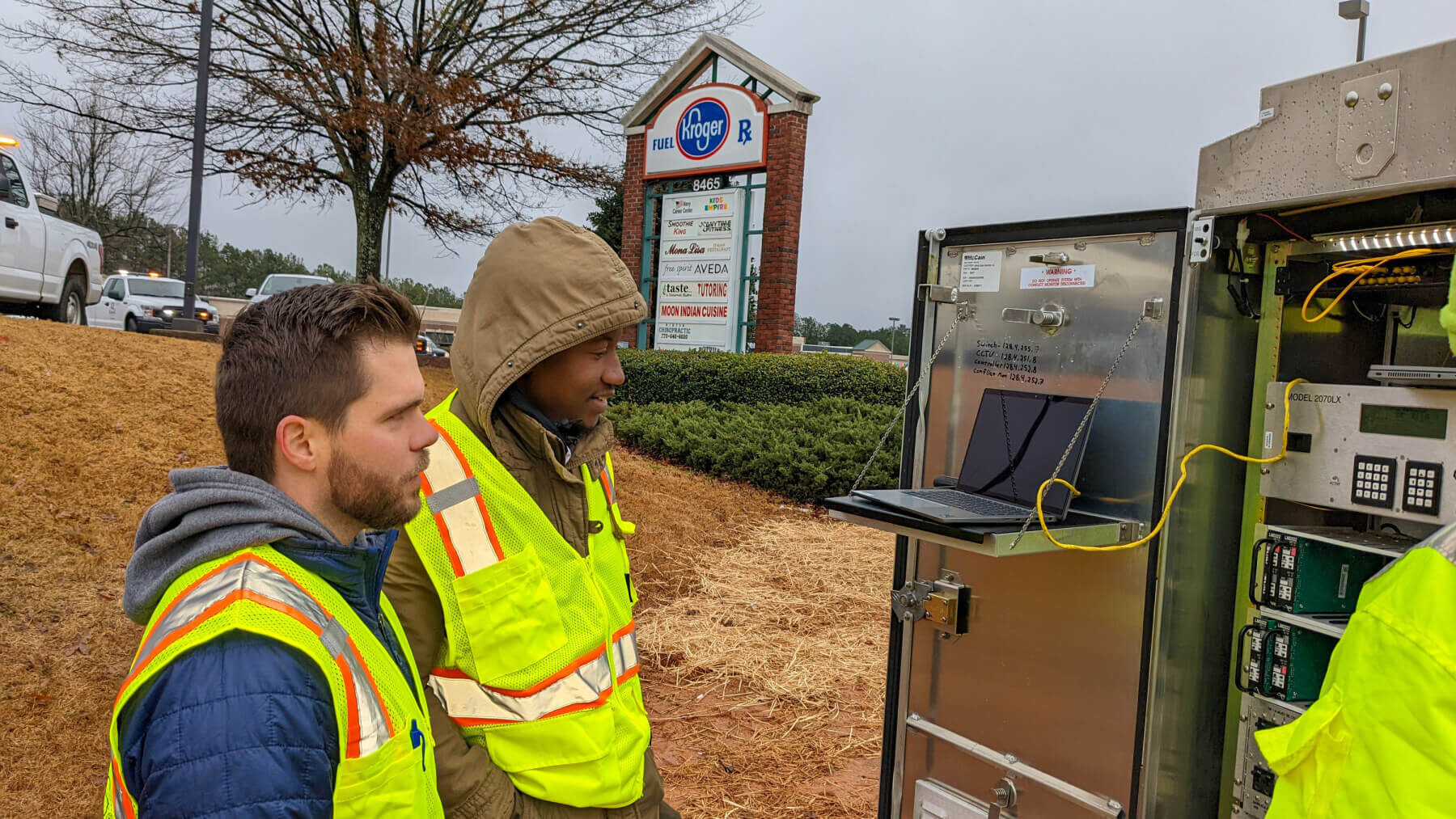 People in yellow vests look at a laptop for GDOT’s SigOps