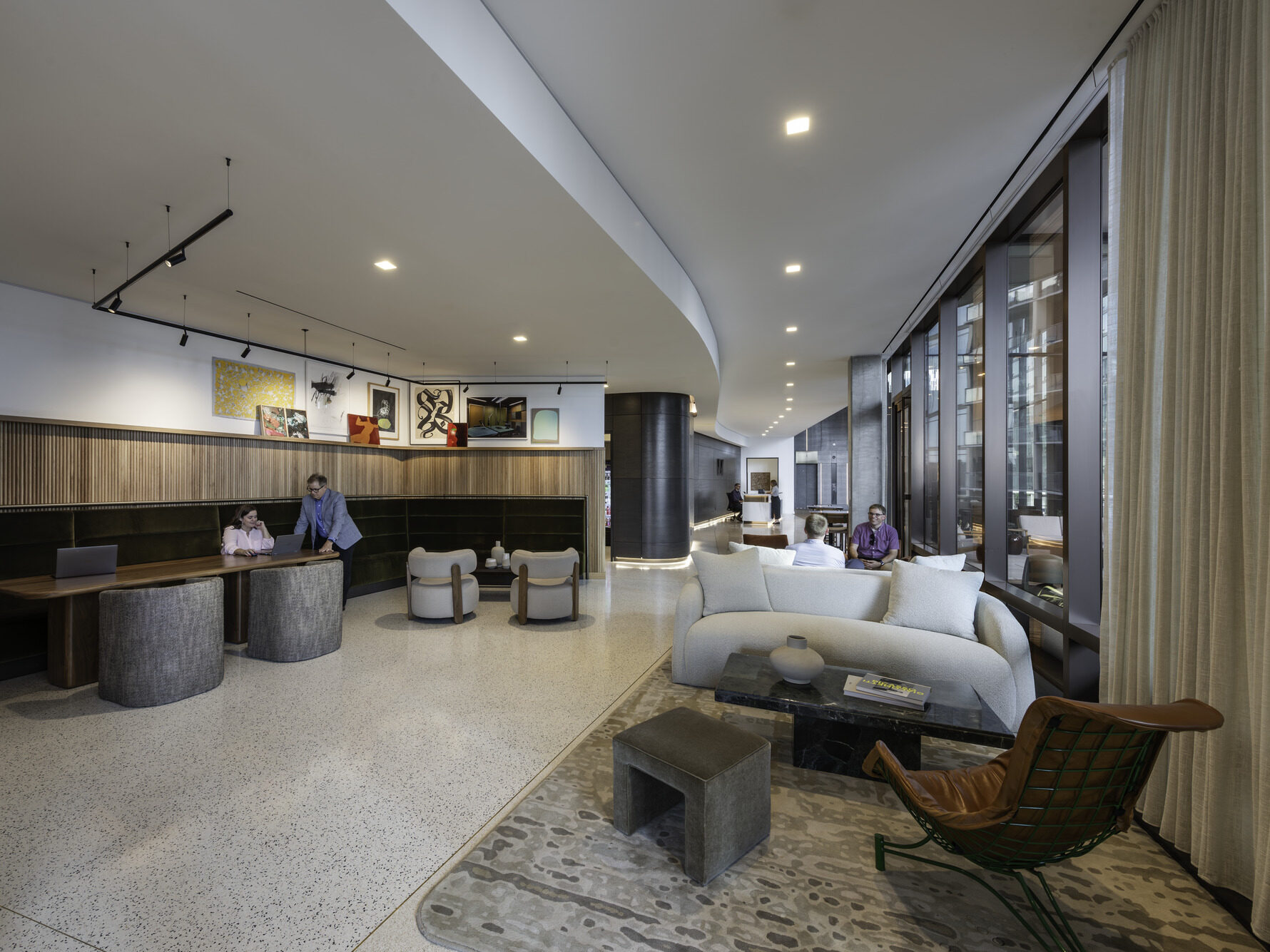 An office lobby with funky furniture and a wall of windows to the right with banquet seating to the left.