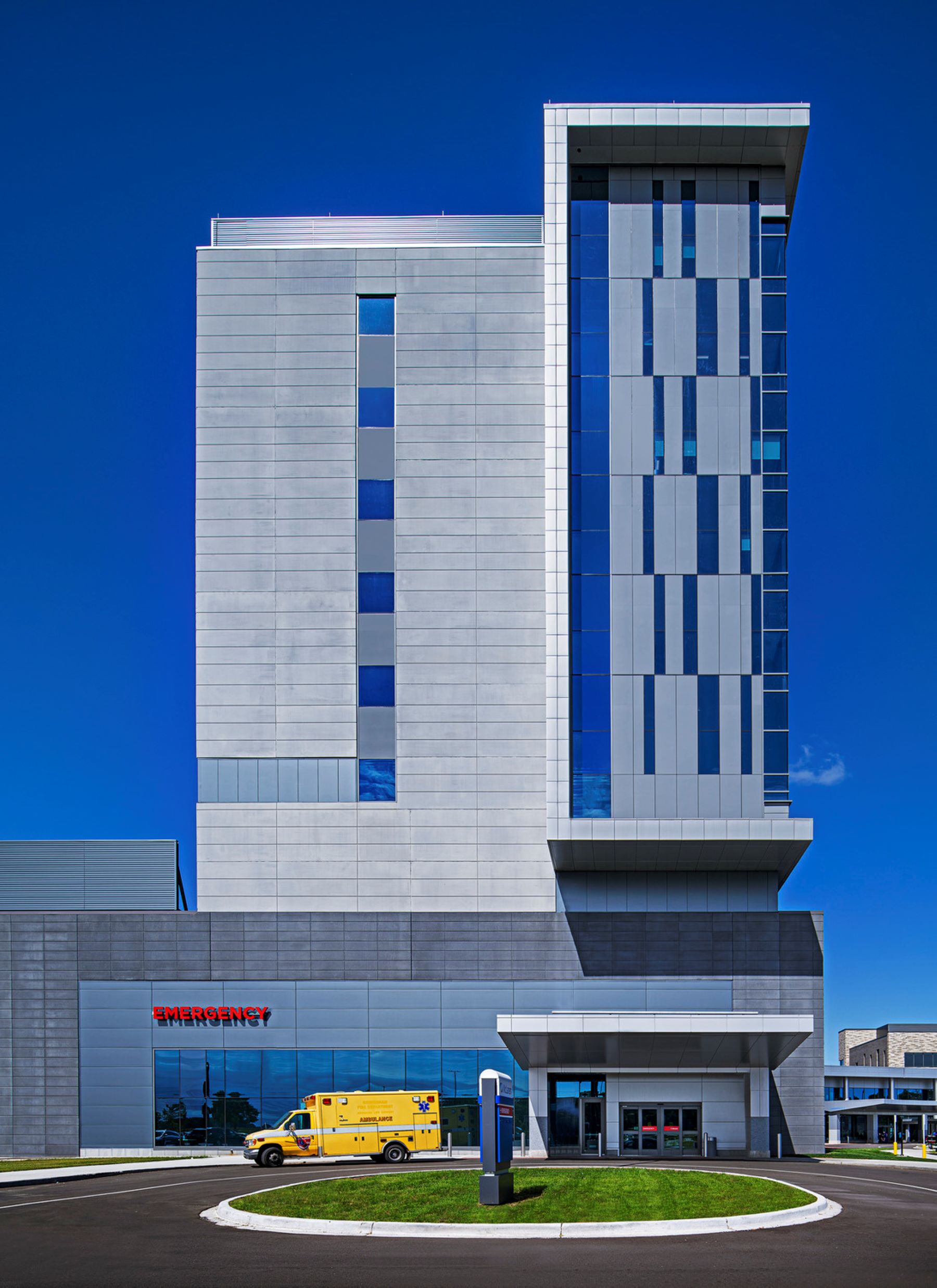 A yellow ambulance outside the entrance to a hospital emergency department