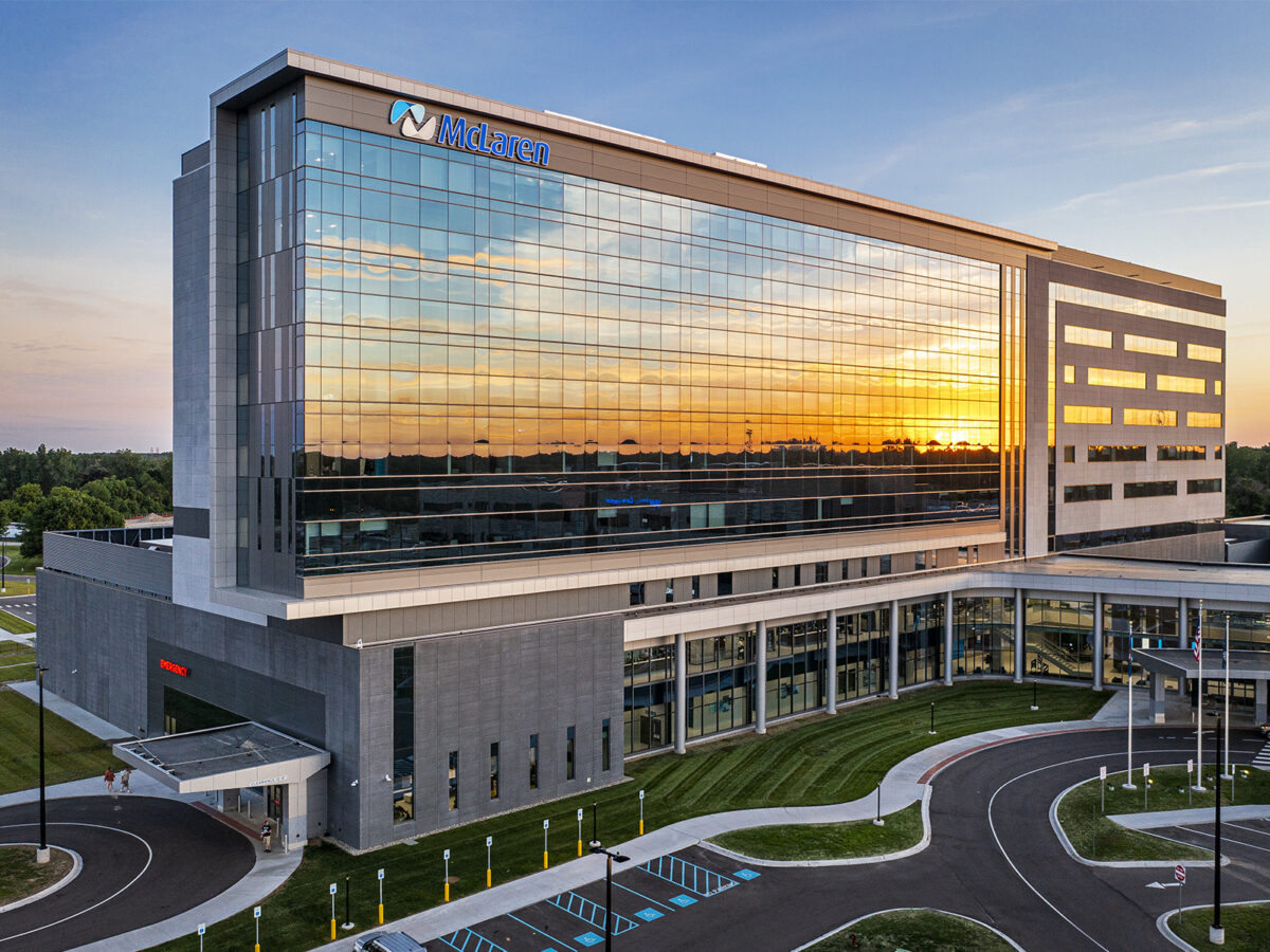 exterior of a nine-story hospital with a large glass façade reflecting the sunset