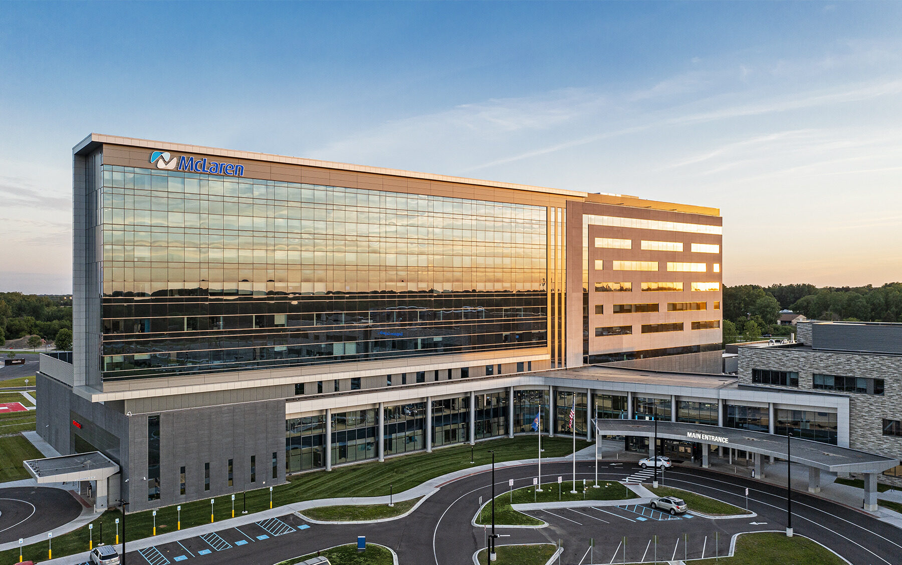 exterior of a nine-story hospital with a large glass façade reflecting the sunset