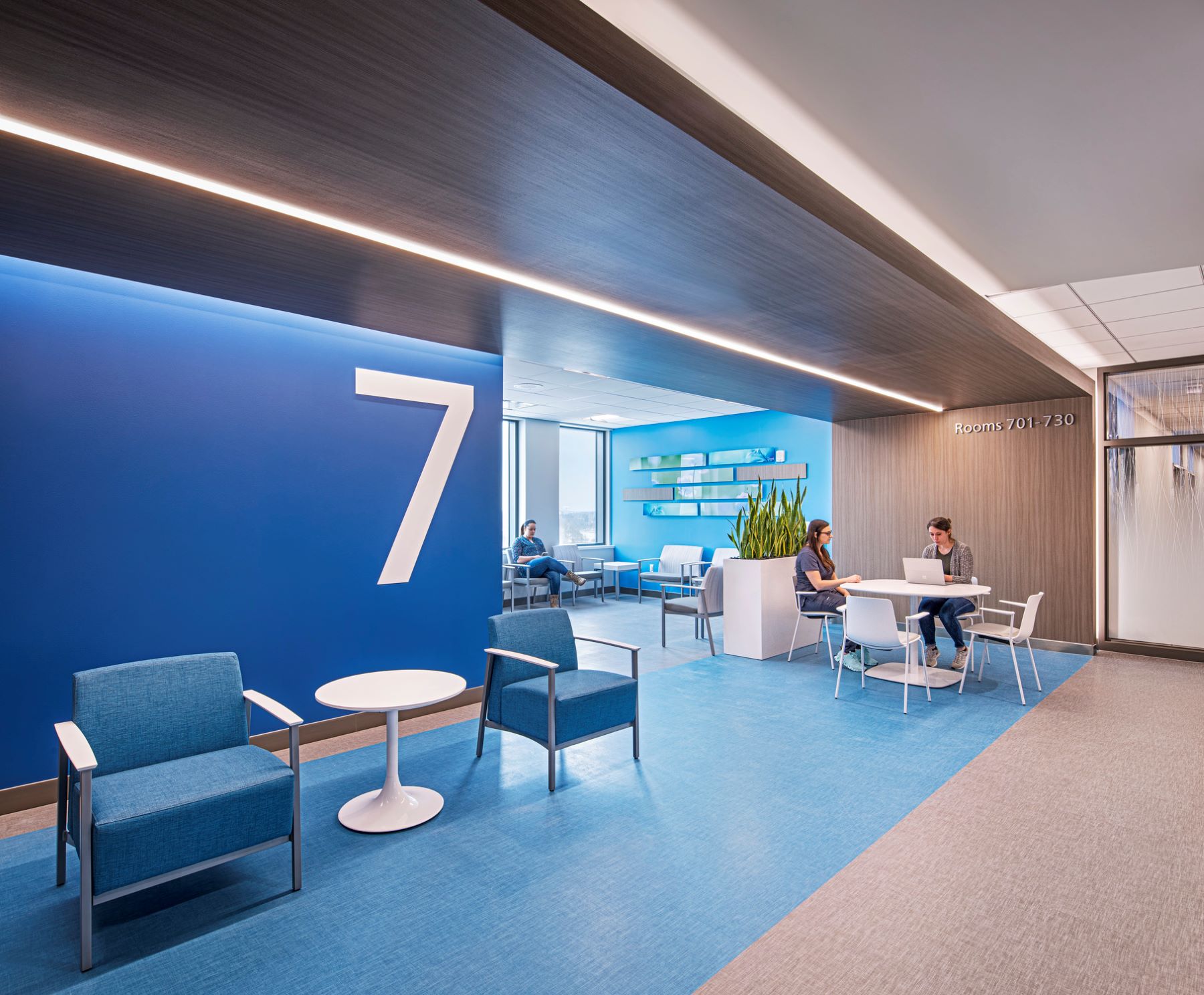 Two people sitting at a white table in a waiting area on the seventh floor of a hospital