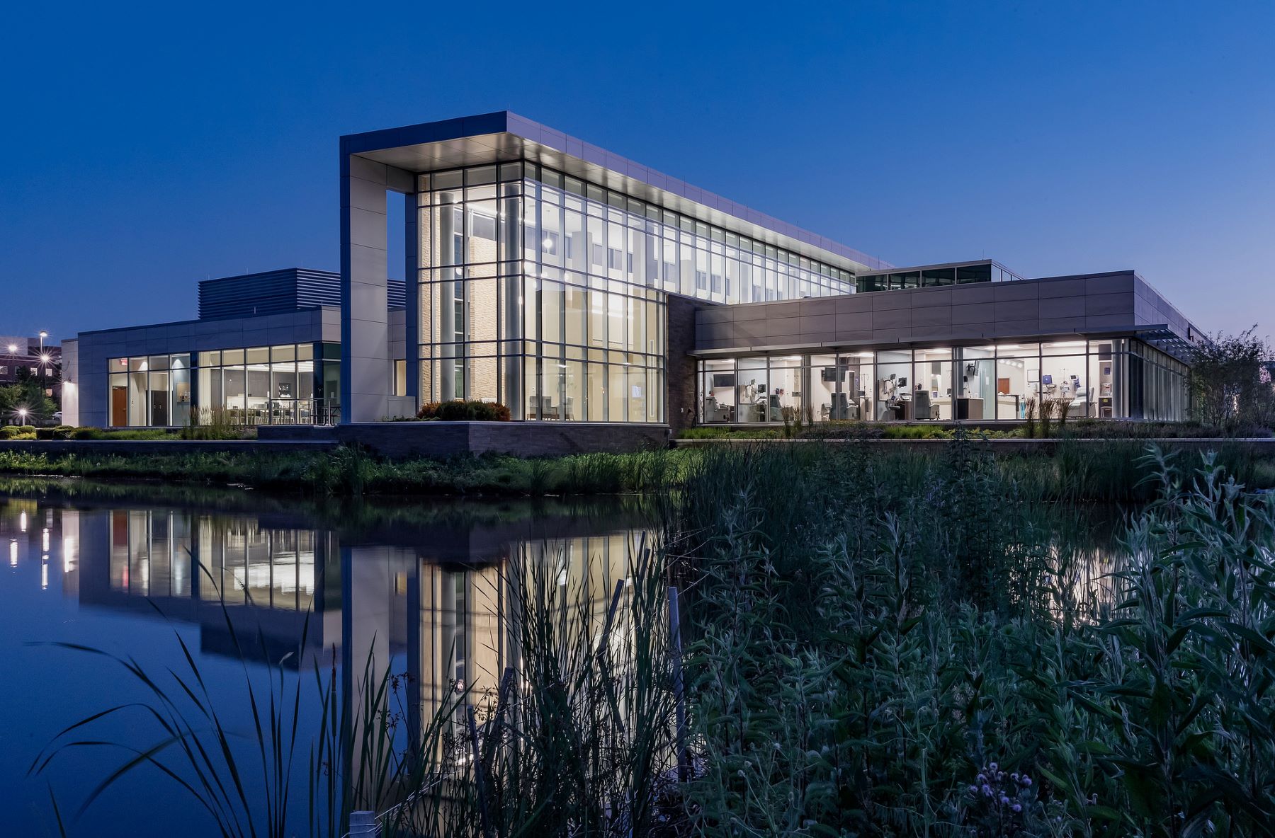 Exterior of a modern building with a pond in front at night