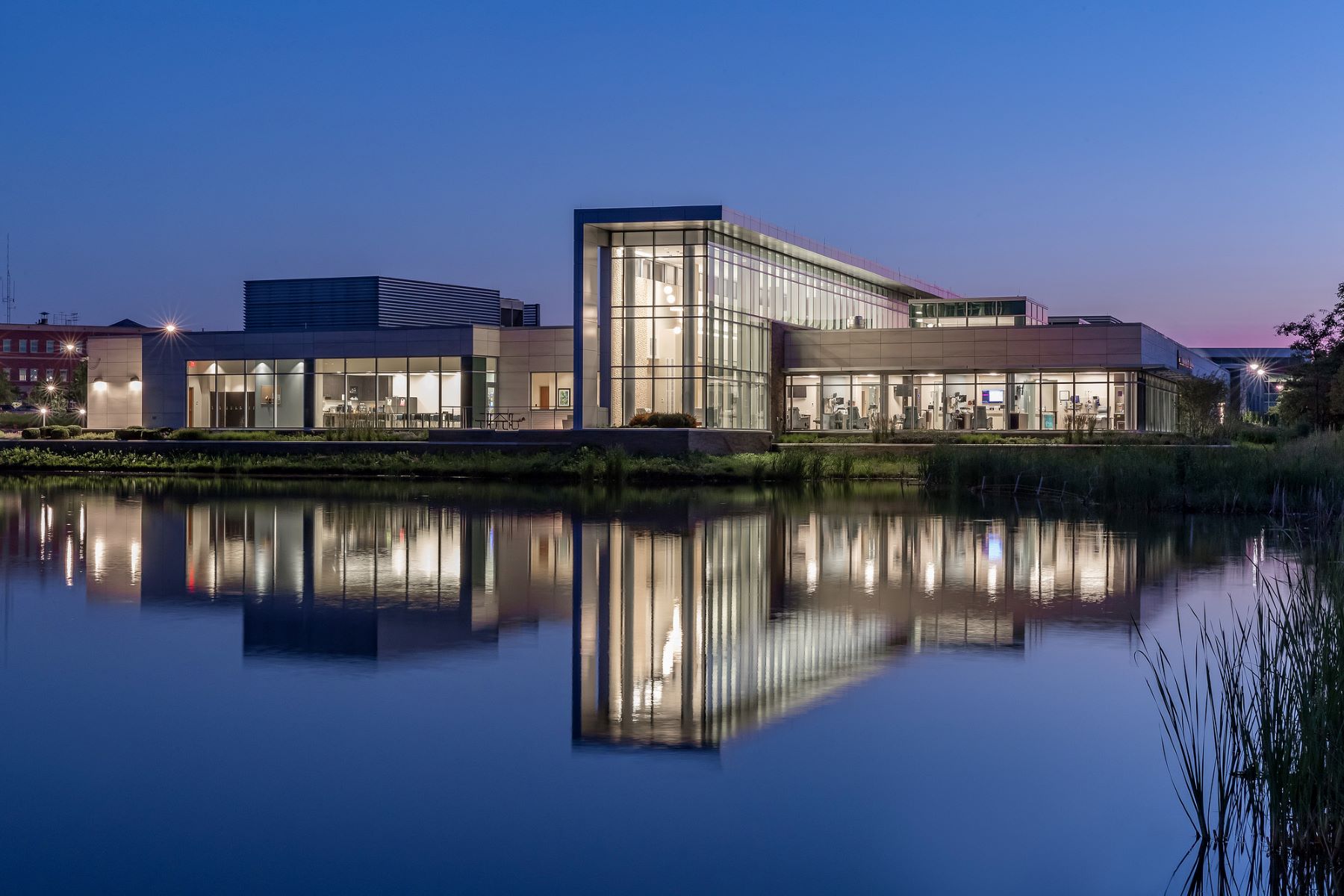 Exterior of a modern building with a pond in front at night