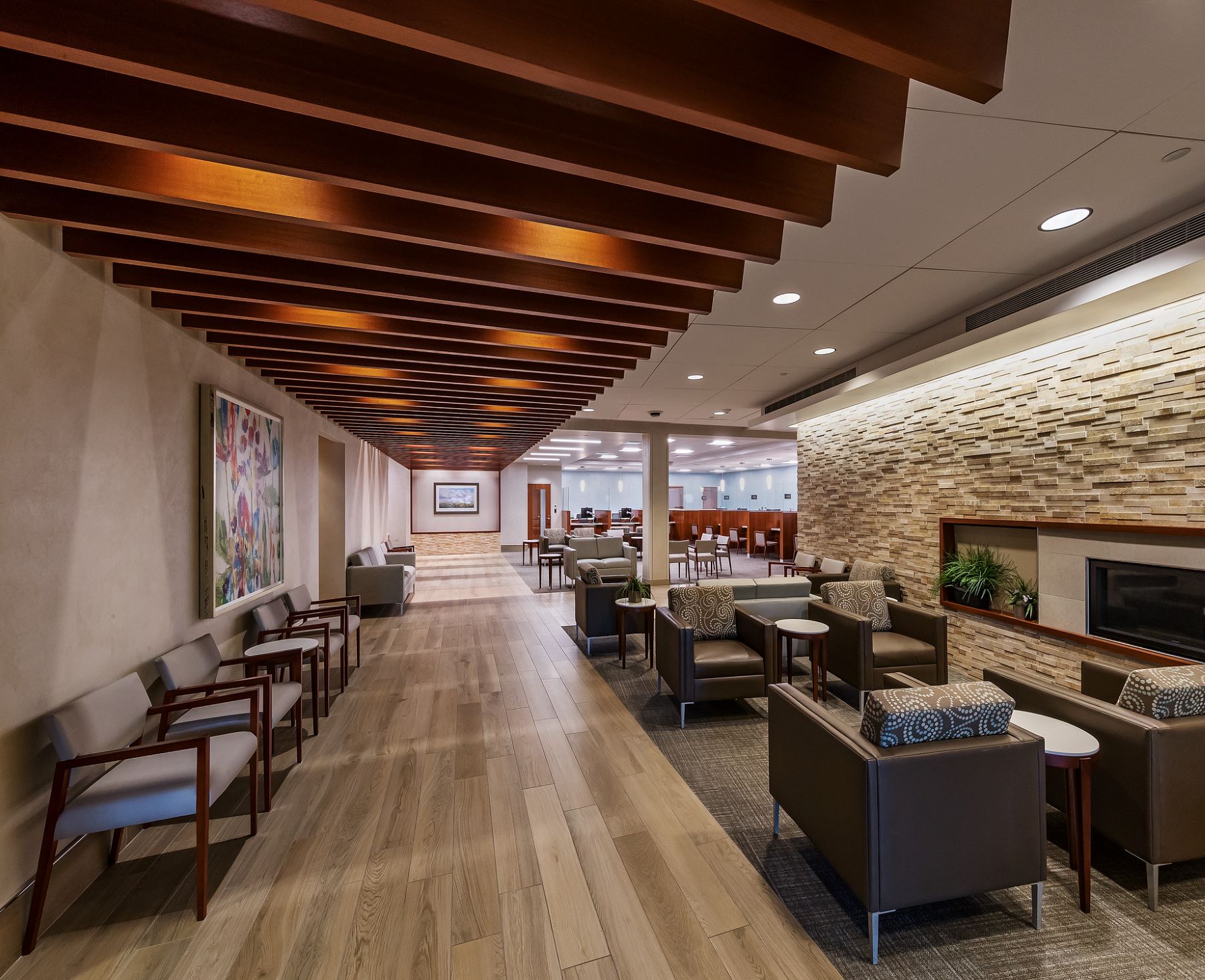 A waiting room with lots of chairs and a stone fireplace and overhead beams