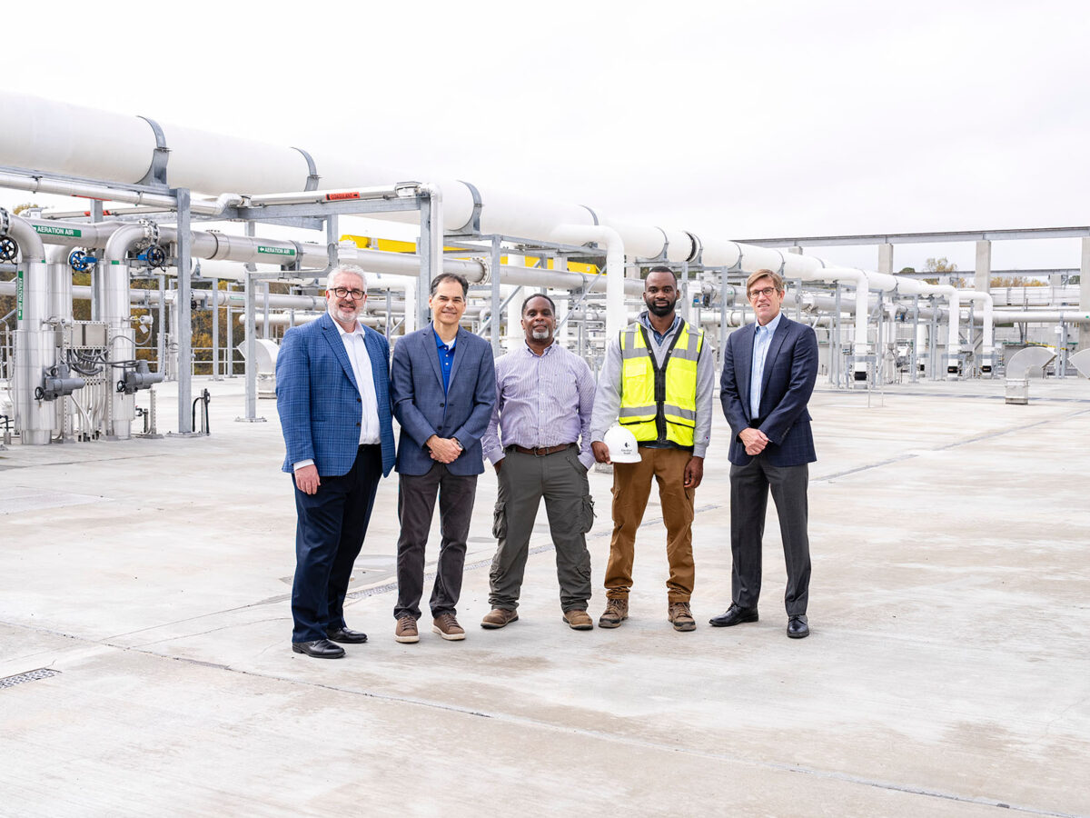 people standing in front of pipes at a wastewater treatment plant