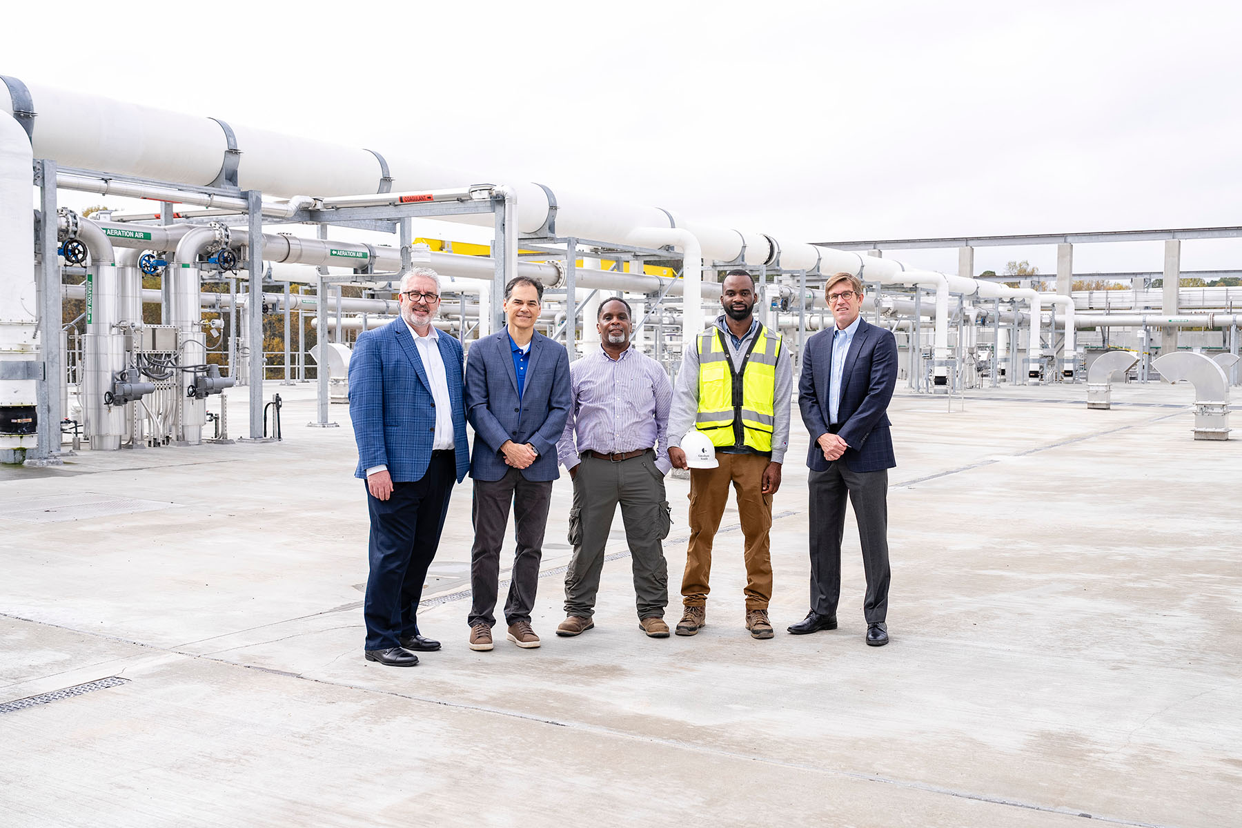 people standing in front of pipes at a wastewater treatment plant