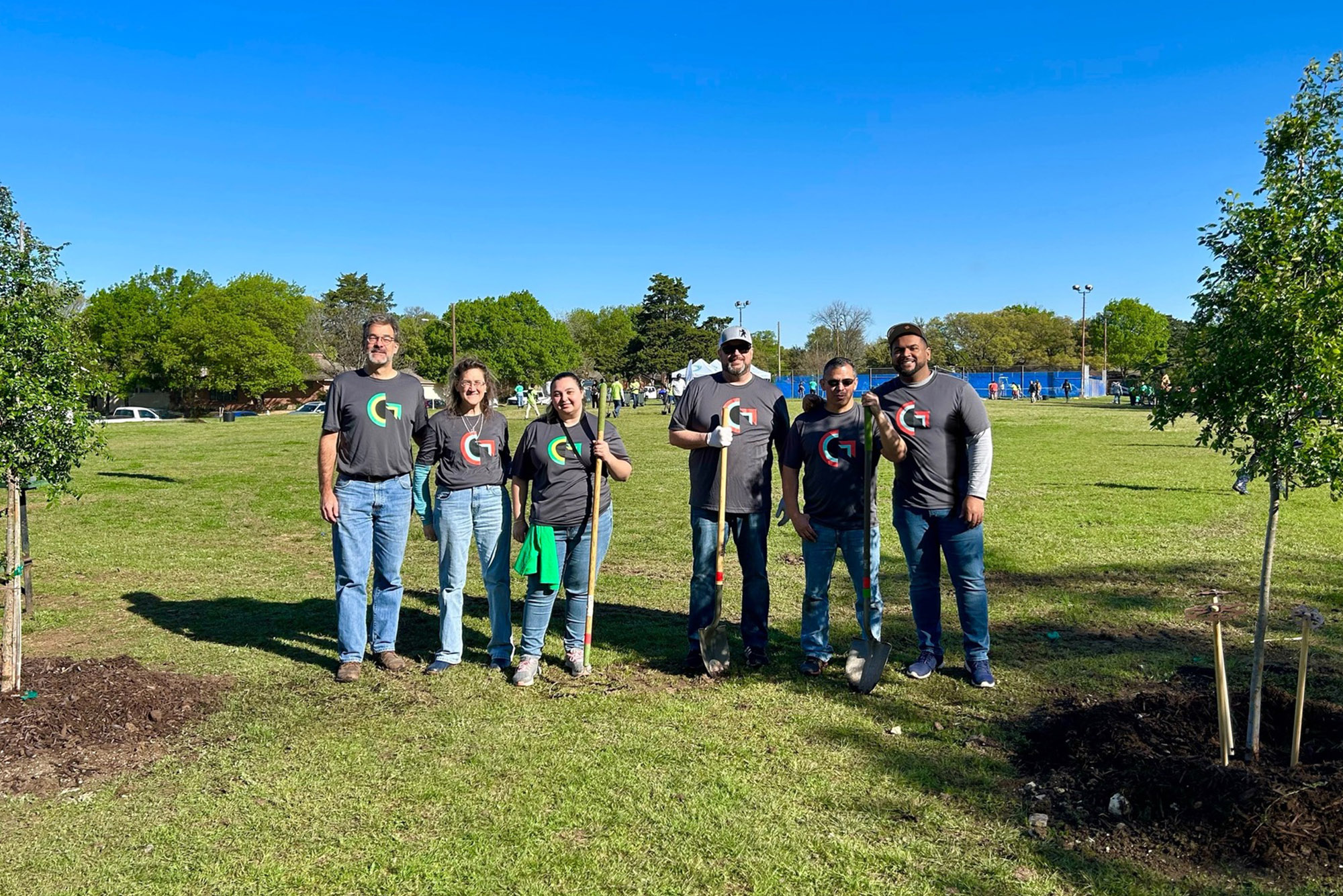 People holding shovels after planting trees in a Dallas park