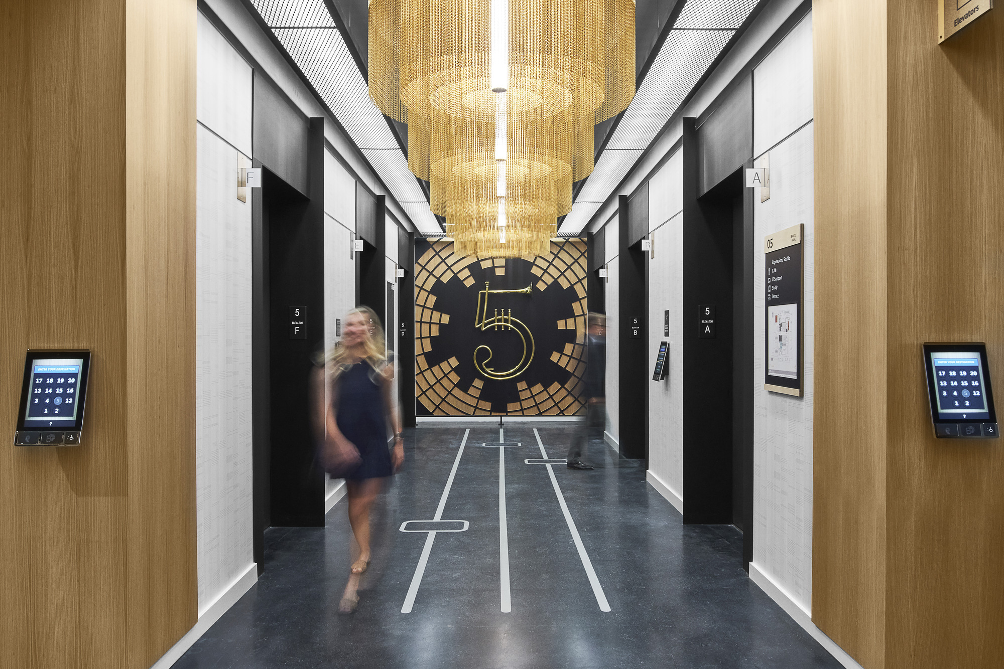 a person exiting a fifth floor elevator lobby that features a large number made of instruments for wayfinding