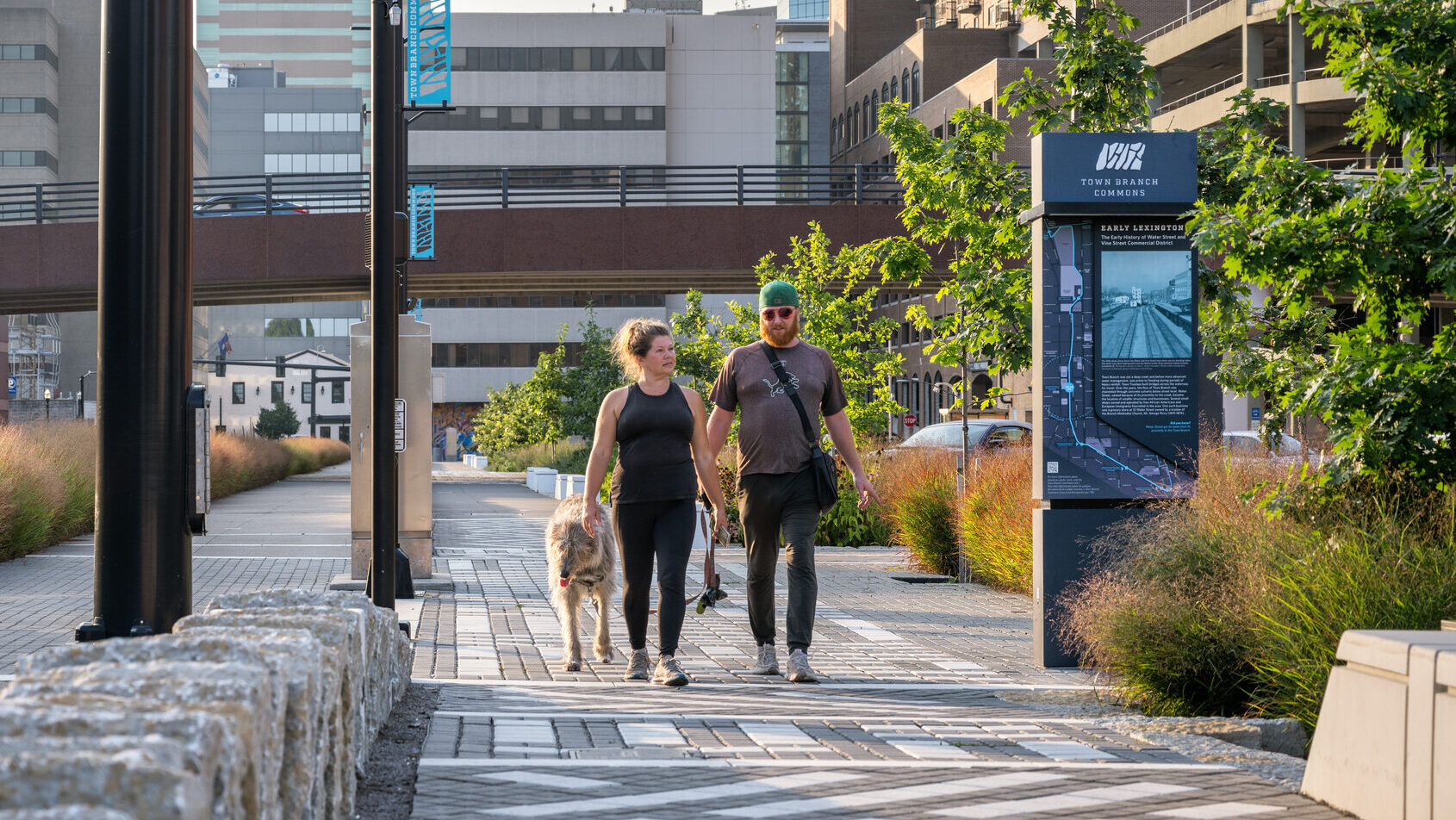 People walking their dog along a sidewalk