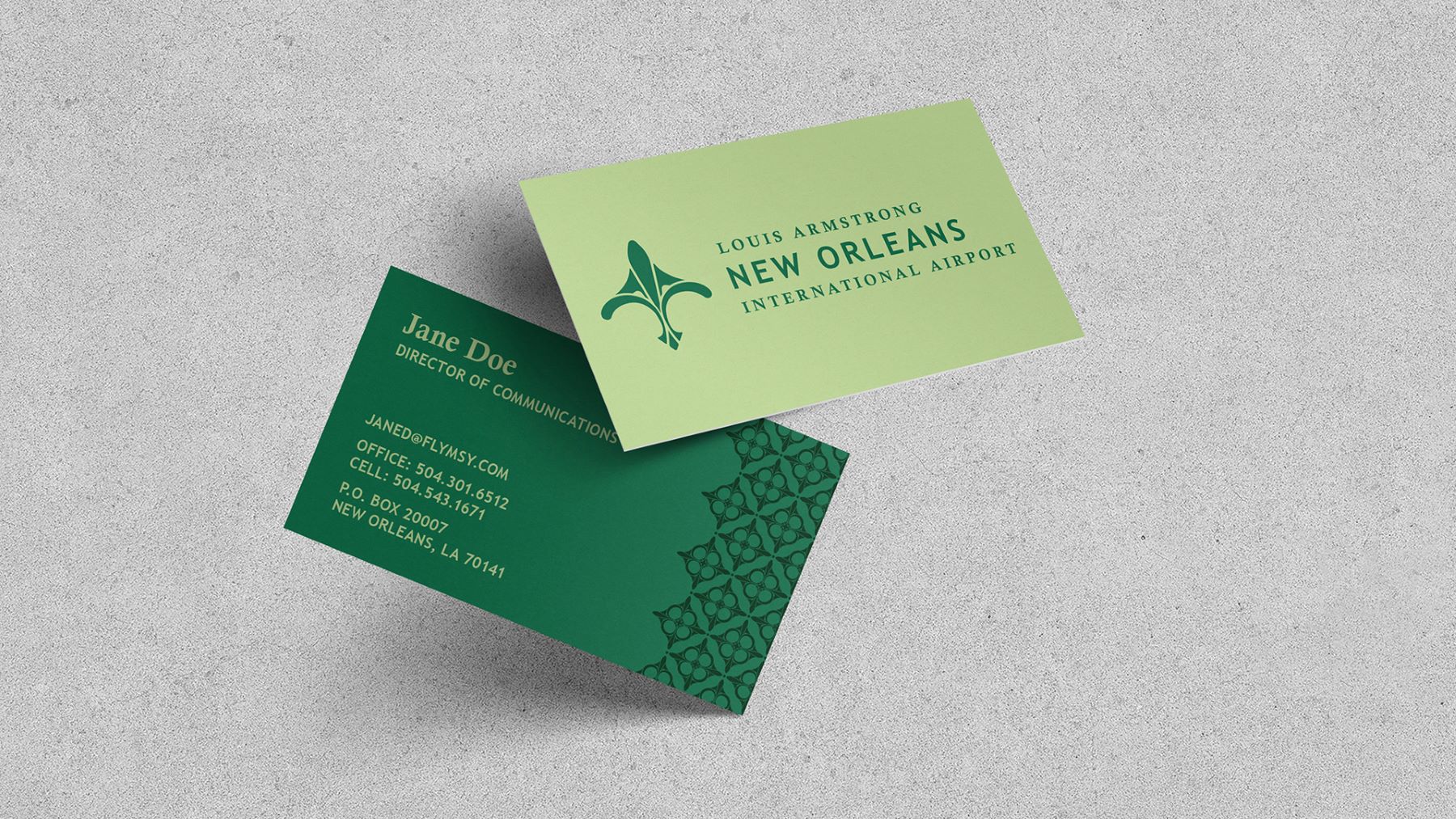 lapel pin and green business cards featuring new orleans international airport's new logo