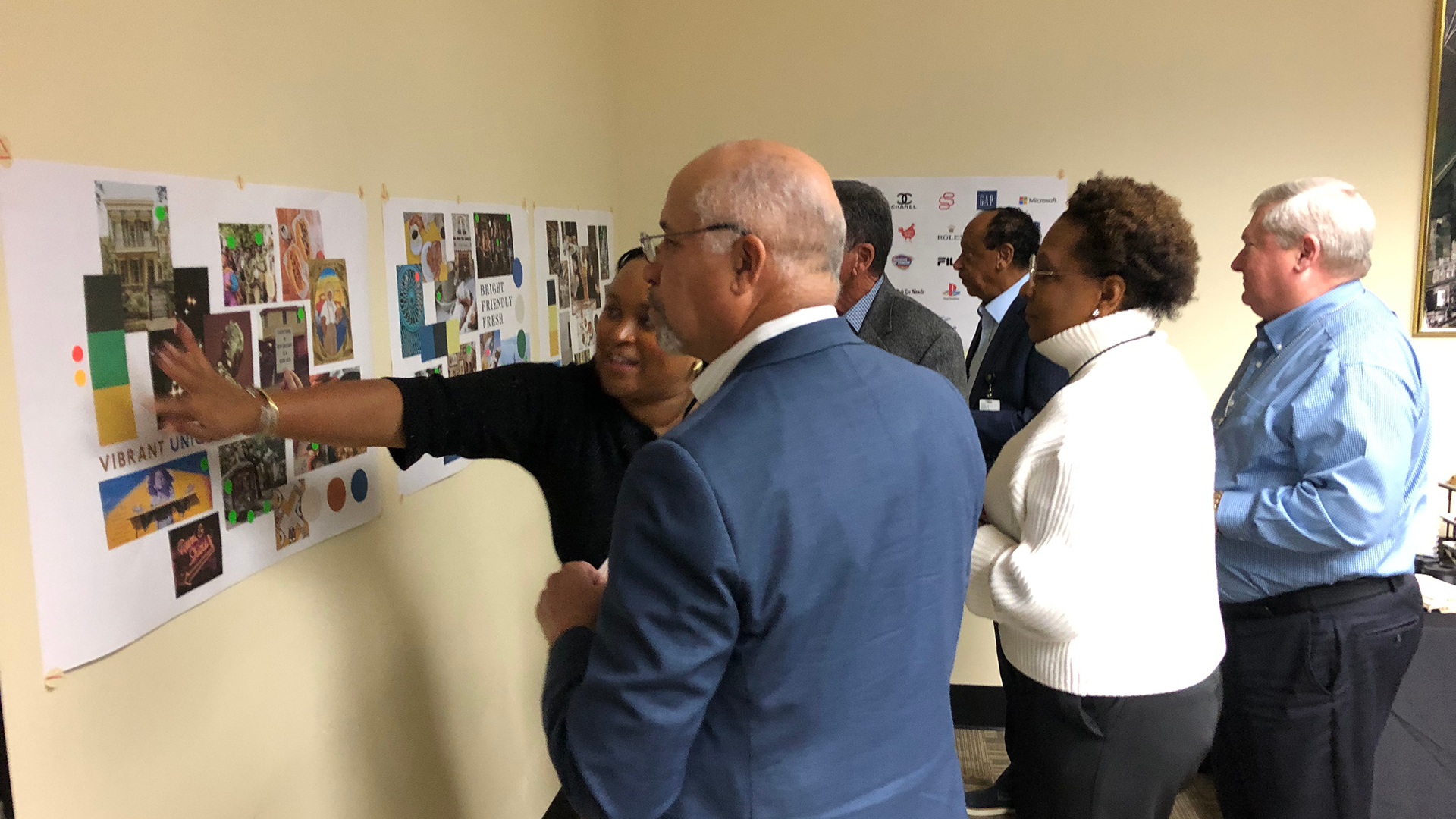 people placing post it notes on a poster board containing inspiration images for new orleans international airport's new brand identity